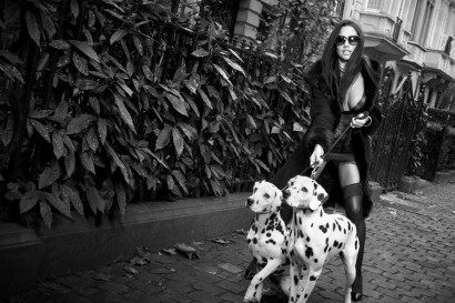 Photo en noir et blanc d'une belle femme sexy en lingerie dans la rue en porte-jarretelles avec ses deux dalmatiens.