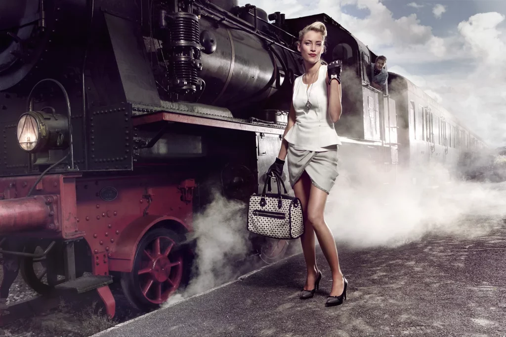 Contraste visuel entre l'élégance d'Émilie Dupuis et la locomotive à vapeur.