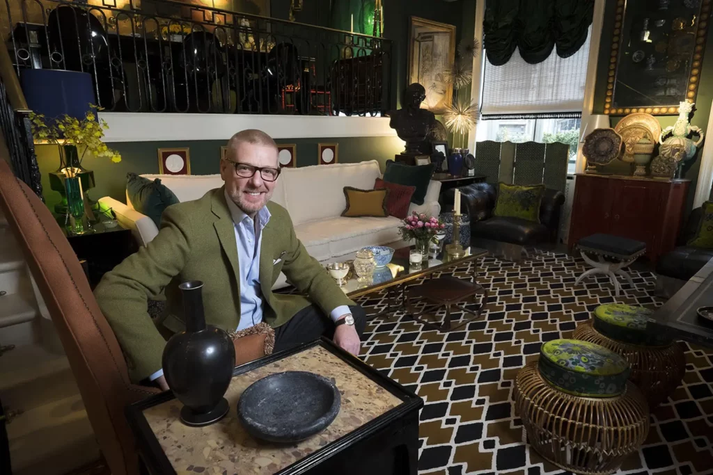 Gérald Watelet assis dans son salon décoré d'antiquités à Bruxelles.