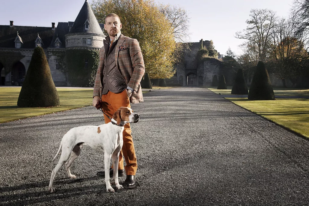 Gérald Watelet en tenue Crossword avec un chien Pointer Anglais dans l'allée d'un château, style gentleman farmer.