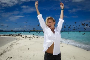 Julie Taton souriante sur un banc de sable aux Maldives, shooting mode au Kanuhura pour Paris Match.
