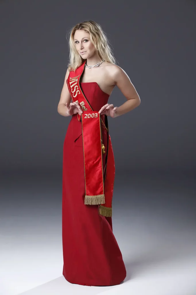 Julie Taton portant sa robe rouge et son écharpe de Miss Belgique 2003 lors de ses 10 ans de carrière.