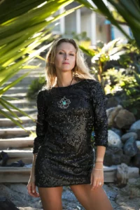 Julie Taton en robe courte à paillettes noires, les bras le long du corps, toisant l'objectif d'un regard intense. Cadrage portrait réalisé par le photographe de célébrités Michel Gronemberger à la Réunion.