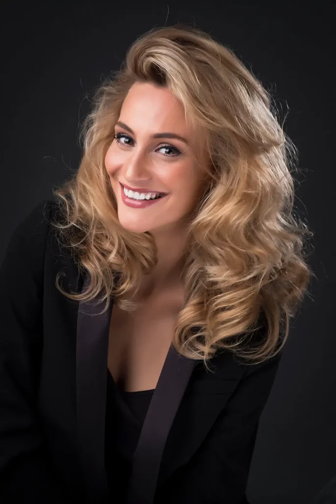 Portrait studio vertical Lima Ché en veste de smoking noir sur fond gris foncé.