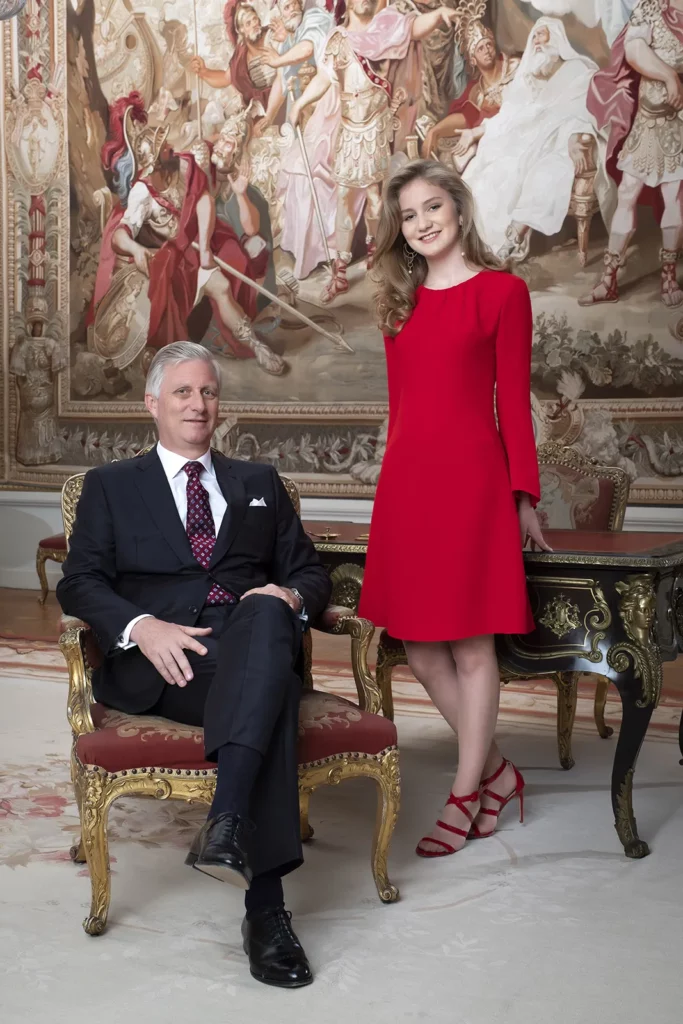 Portrait vertical du Roi Philippe et de la Princesse Elisabeth en robe rouge dans le bureau royal de Laeken.