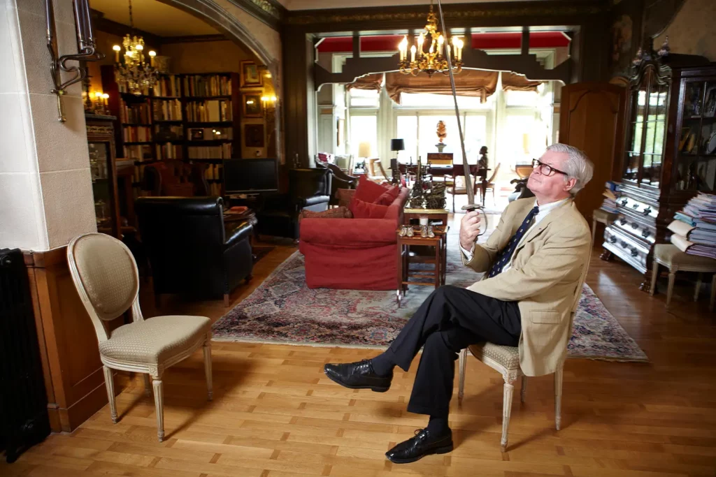 Portrait de l'avocat Xavier Magnée brandissant un sabre dans son salon bourgeois à Bruxelles, photographie de Marc Gronemberger.