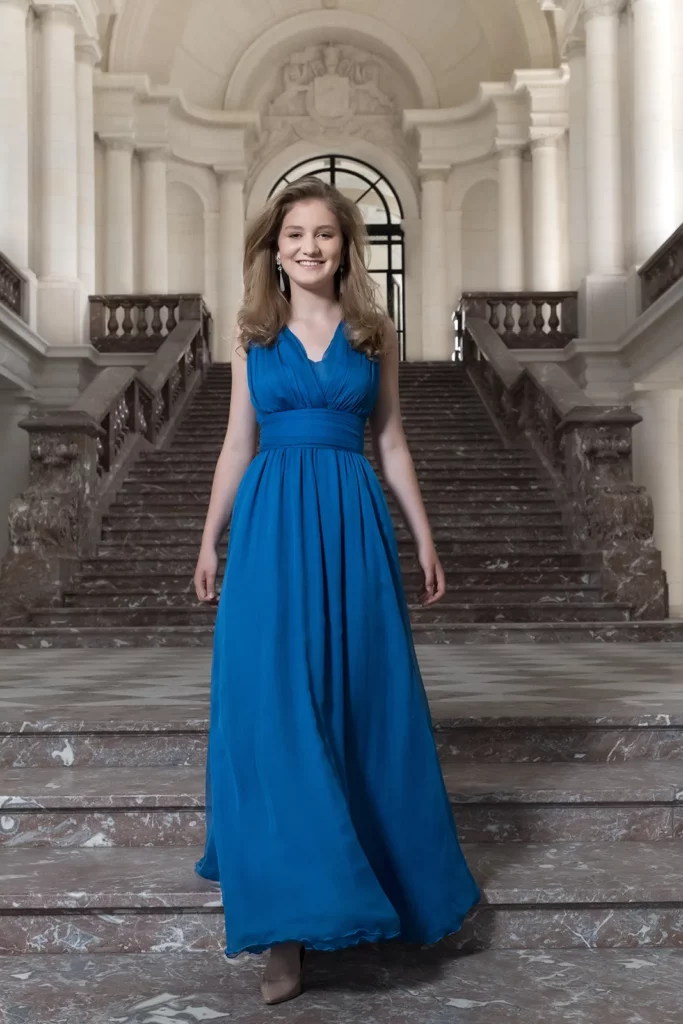 Portrait de la Princesse Elisabeth en robe bleue devant l'entrée de la grande galerie du Château de Laeken.