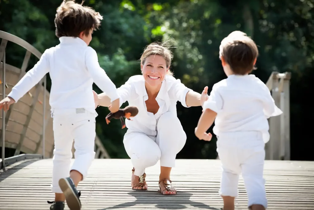 Armelle Gysen accroupie les bras ouverts accueillant ses deux fils Gatien et Douglas sur la promenade verte.