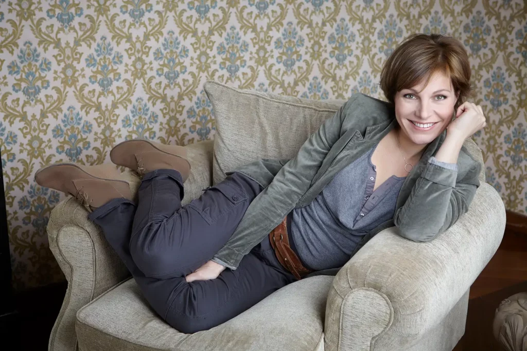 Armelle Gysen souriante sur un fauteuil vert pâle au Château de Ry.