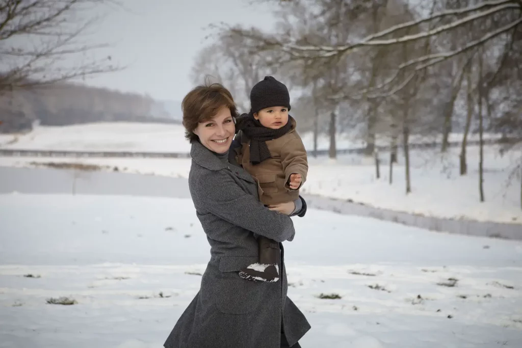 Armelle Gysen souriante portant son fils Gatien devant l'étang gelé du Château de Ry.