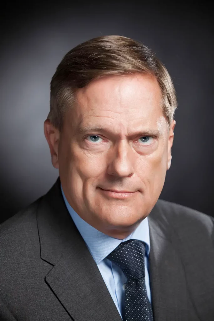 Portrait de dirigeant exprimant le leadership, costume gris et cravate bleue.