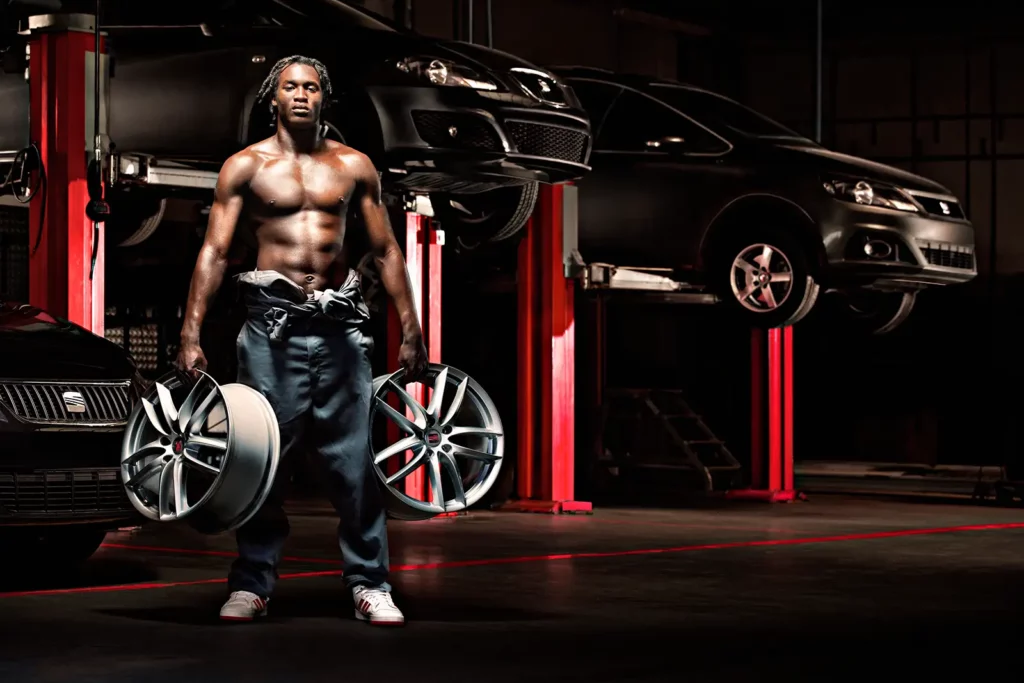 Photo horizontale de Romelu Lukaku torse nu en salopette dans un garage, cadré à droite pour mise en page éditoriale.