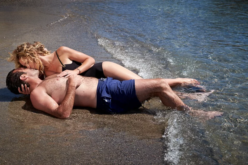 Sandrine Corman et Michel Bouhoulle s'embrassant sur le sable au bord de l'eau dans la baie de Mirabello, Crète.