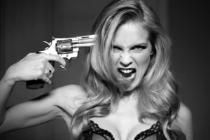 Portrait serré de Sophie Pendeville avec un revolver contre la tempe, criant pour une séance photo artistique.