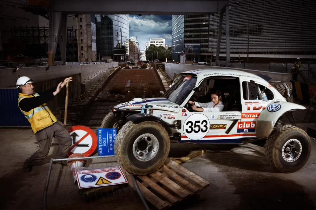 Vanina Ickx au volant du Buggy au rond-point Schuman à Bruxelles. Mise en scène avec un ouvrier et des palettes de chantier rue de la Loi par Michel Gronemberger.