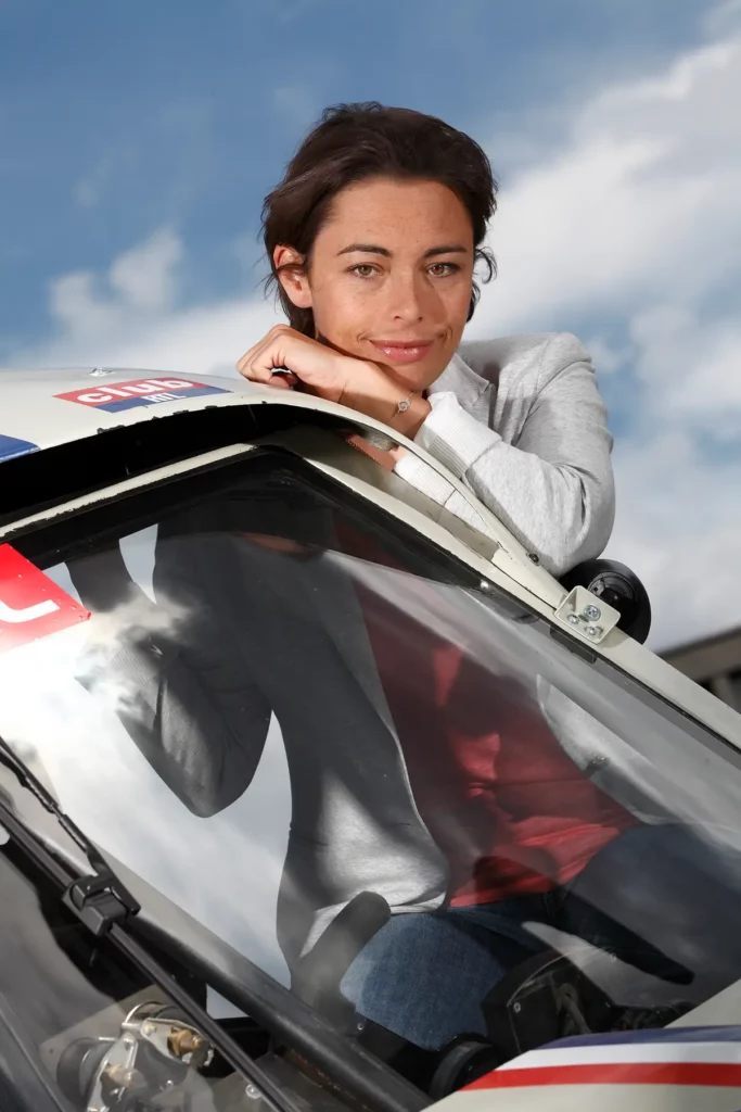 Portrait de Vanina Ickx assise sur la portière du Buggy VW de Stéphane Henrard, regardant l'objectif. Photographie par Michel Gronemberger à Bruxelles.