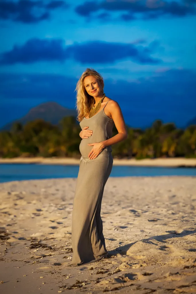 Portrait vertical de Julie Taton enceinte regardant face caméra au coucher du soleil à l'île Maurice, robe kaki volant au vent.