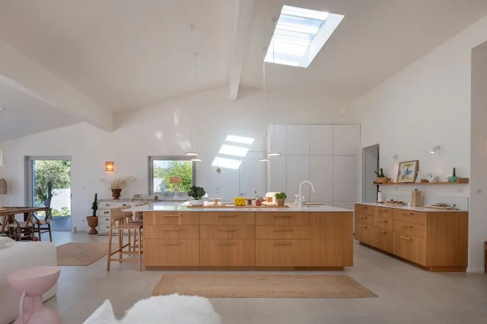 Intérieur minimaliste d'une maison contemporaine avec sol en béton, mobilier en rotin et puits de lumière près de Lyon pour shooting mode et bien-être.