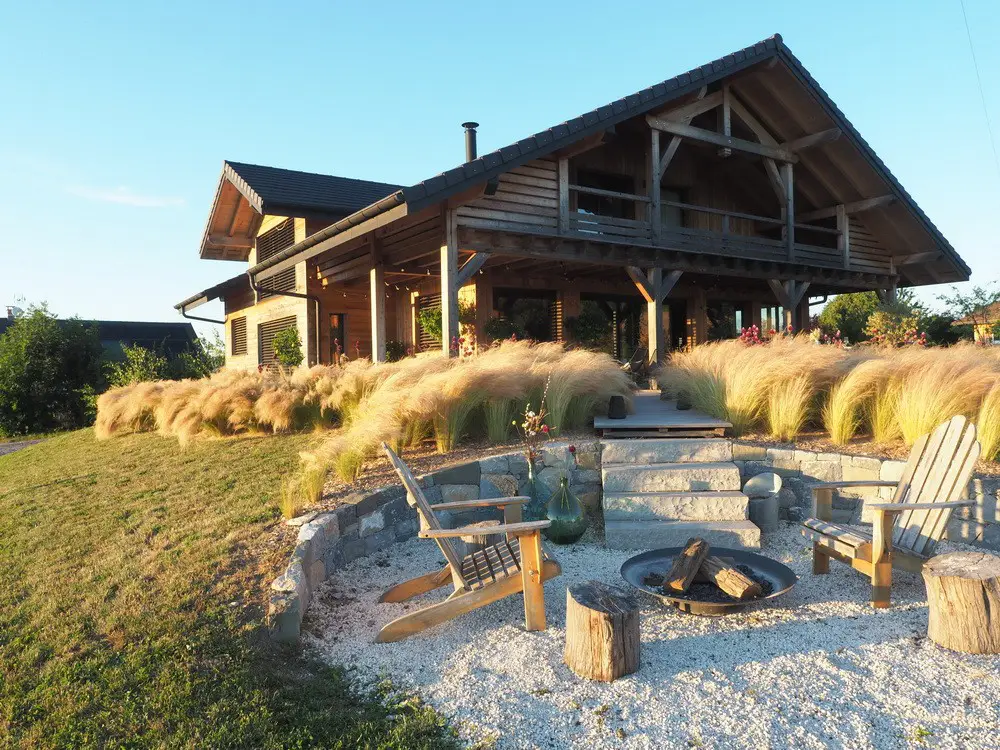 Salon moderne avec baies vitrées panoramiques, parquet massif et murs en bois près d'Annecy pour shooting de mobilier et mode.