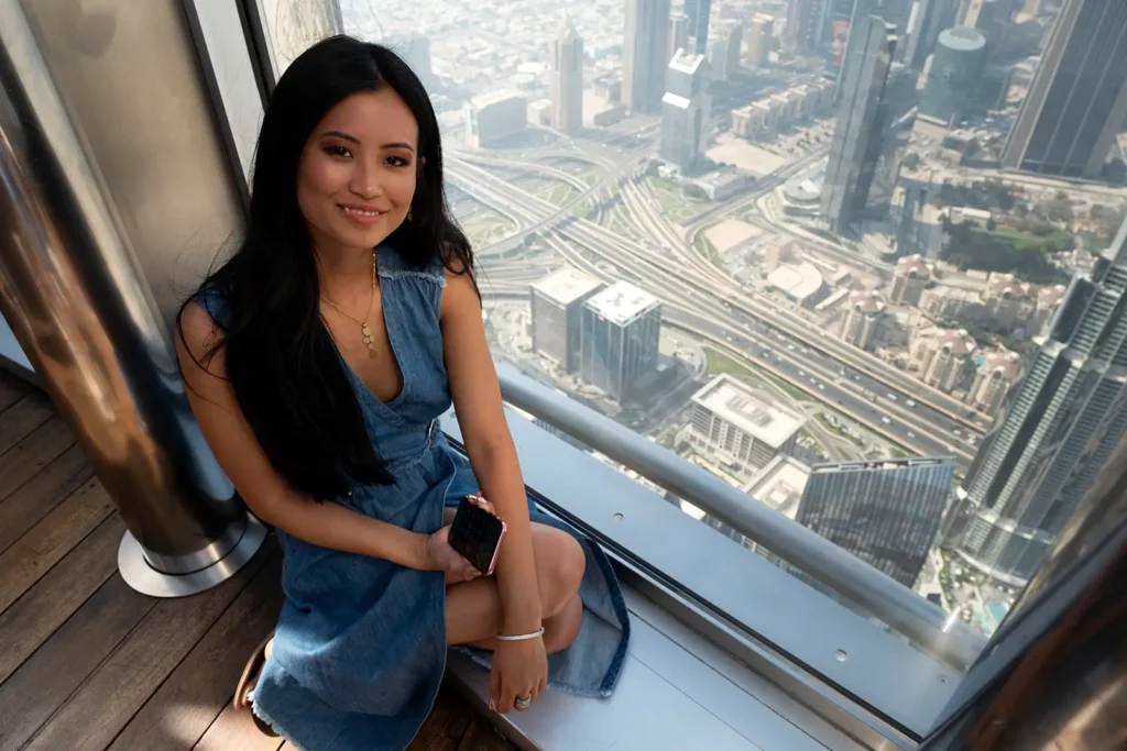Angéline Flor Pua (Miss Belgique) assise au sommet de la Burj Khalifa dominant la ville de Dubaï.