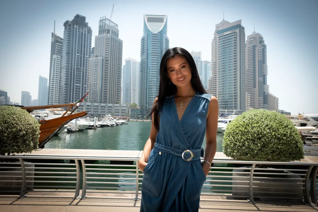 Angéline Flor Pua en robe en jean devant les gratte-ciels de la Marina de Dubaï.