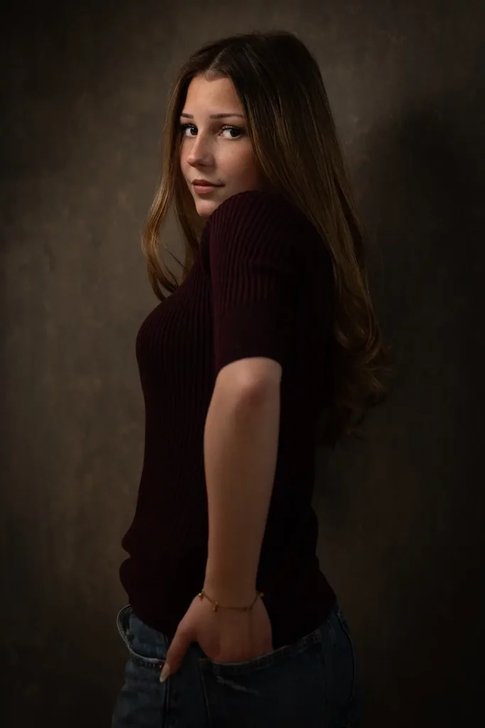 Photographe book modèle Bruxelles, jeune femme posant complètement de profil avec un regard assuré par-dessus l'épaule.