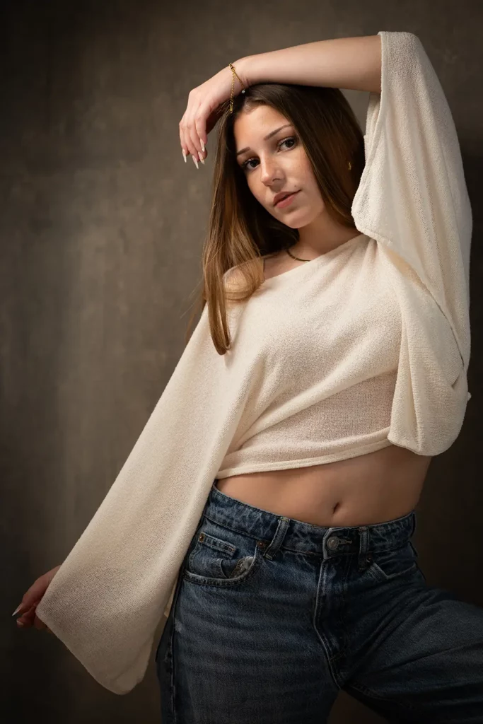 Photographe book modèle Bruxelles, pose éditoriale d'une jeune fille en top court blanc et jeans avec l'avant-bras sur la tête.