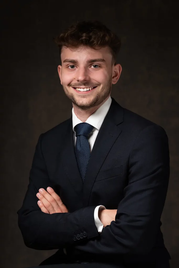 Plan américain d'une photo LinkedIn étudiant les bras croisés avec un sourire rassurant.
