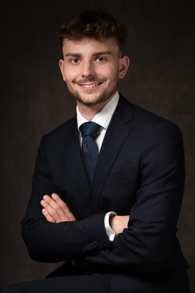 Portrait pro pour une photo LinkedIn étudiant avec un léger sourire bienveillant et les bras croisés.