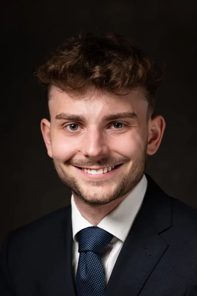 Portrait serré pour une photo LinkedIn étudiant avec un costume bleu et un nœud de cravate impeccable.