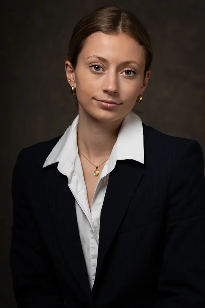 Portrait professionnel CV en plan américain d'une jeune femme en tailleur noir et chemise blanche en studio à Bruxelles.