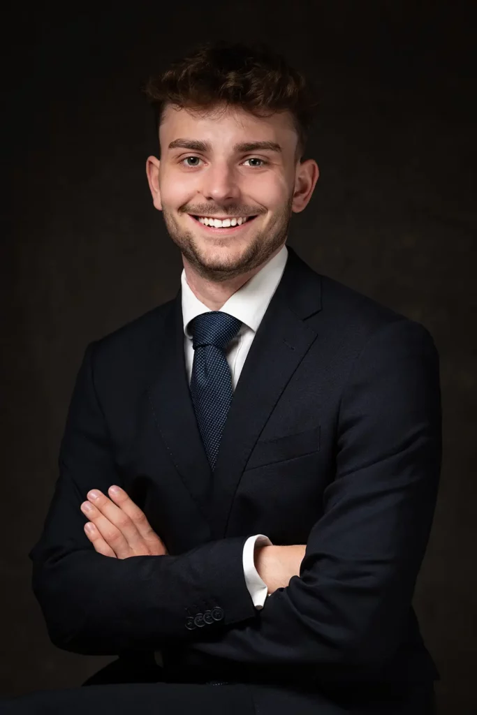 Sourire avenant sur une photo LinkedIn étudiant en costume avec une cravate bleue à points blancs.